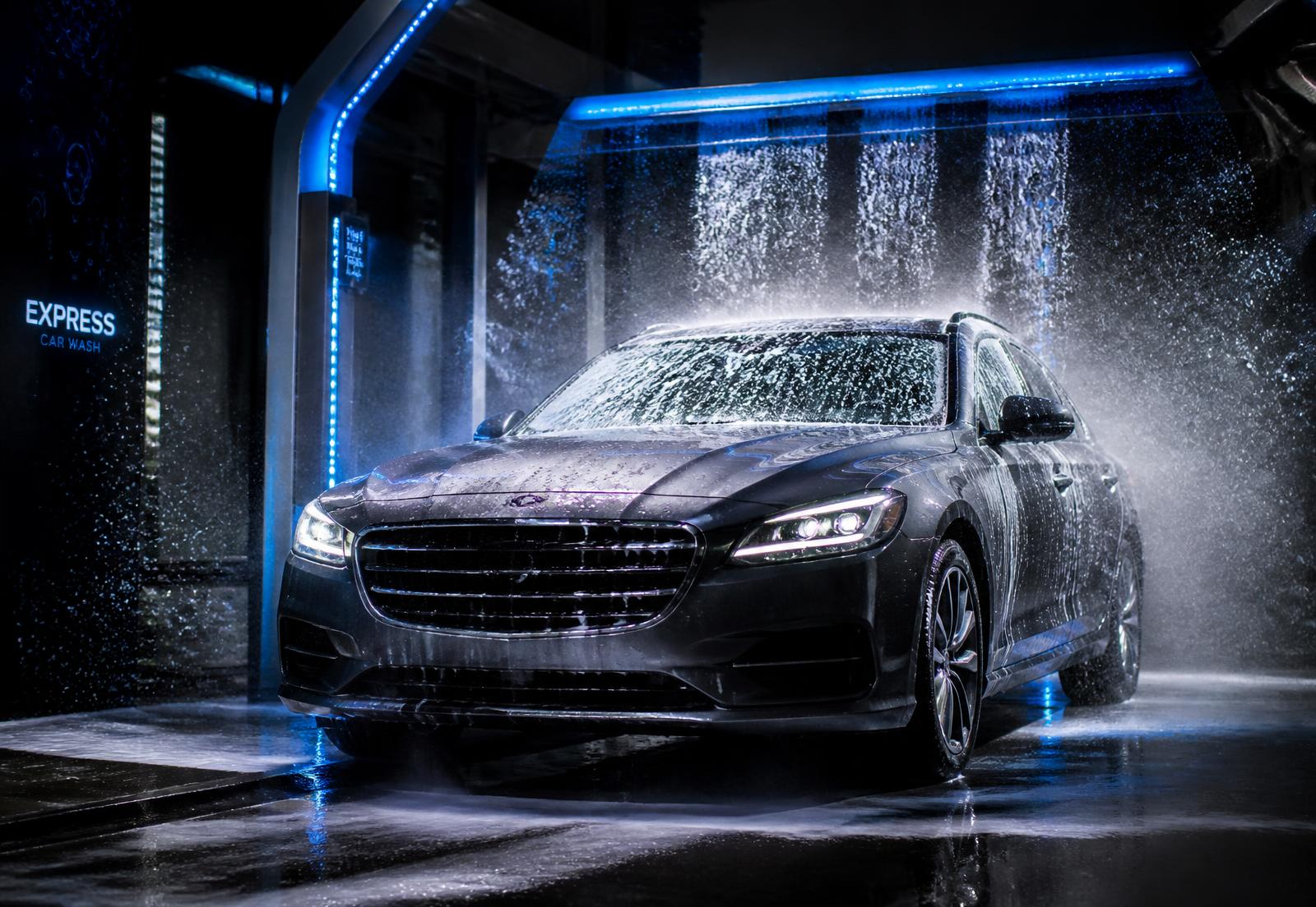 Dark sedan covered in foam inside a modern express car wash tunnel